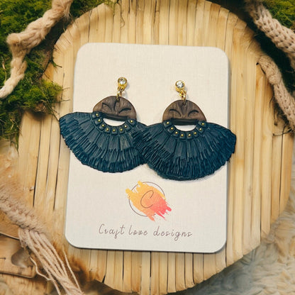 Bold Black and wood-inspired boho fringe earrings with gold accents showcased on a branded card with rustic background.