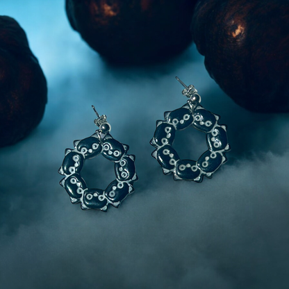 Stylish black cat wreath earrings displayed on a foggy blue background, creating a spooky, mysterious Halloween vibe.