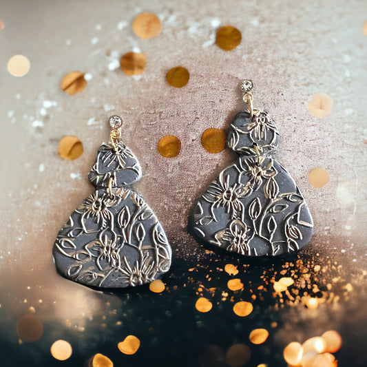 Elegant black polymer clay earrings with gold floral texture, teardrop design, and crystal studs; perfect for statement jewelry.