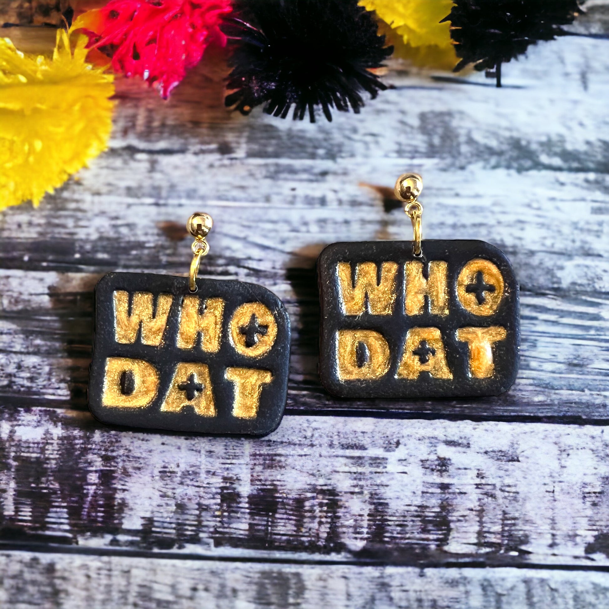 Black handcrafted earrings with metallic gold WHO DAT lettering, a statement design perfect for fans of festive events or game day outfits. 