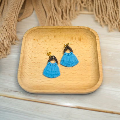 Handmade blue fringe drop earrings with a dark wood accent and gold hardware, placed in a wooden tray with a cozy textile backdrop.