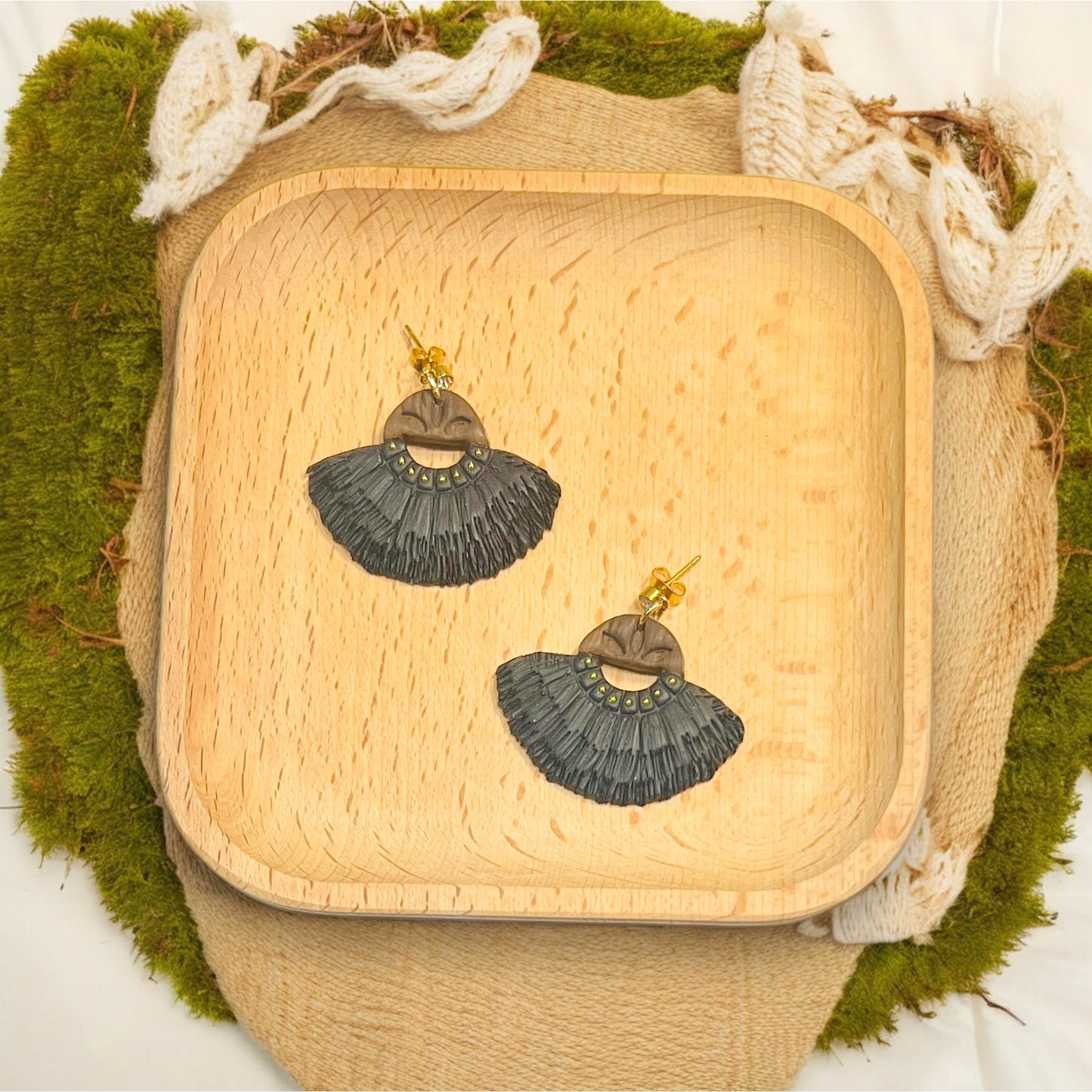 Statement boho navy fringe earrings with wood top detail resting on a rustic wood tray, surrounded by natural accents.