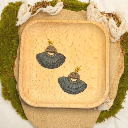 Statement boho navy fringe earrings with wood top detail resting on a rustic wood tray, surrounded by natural accents.