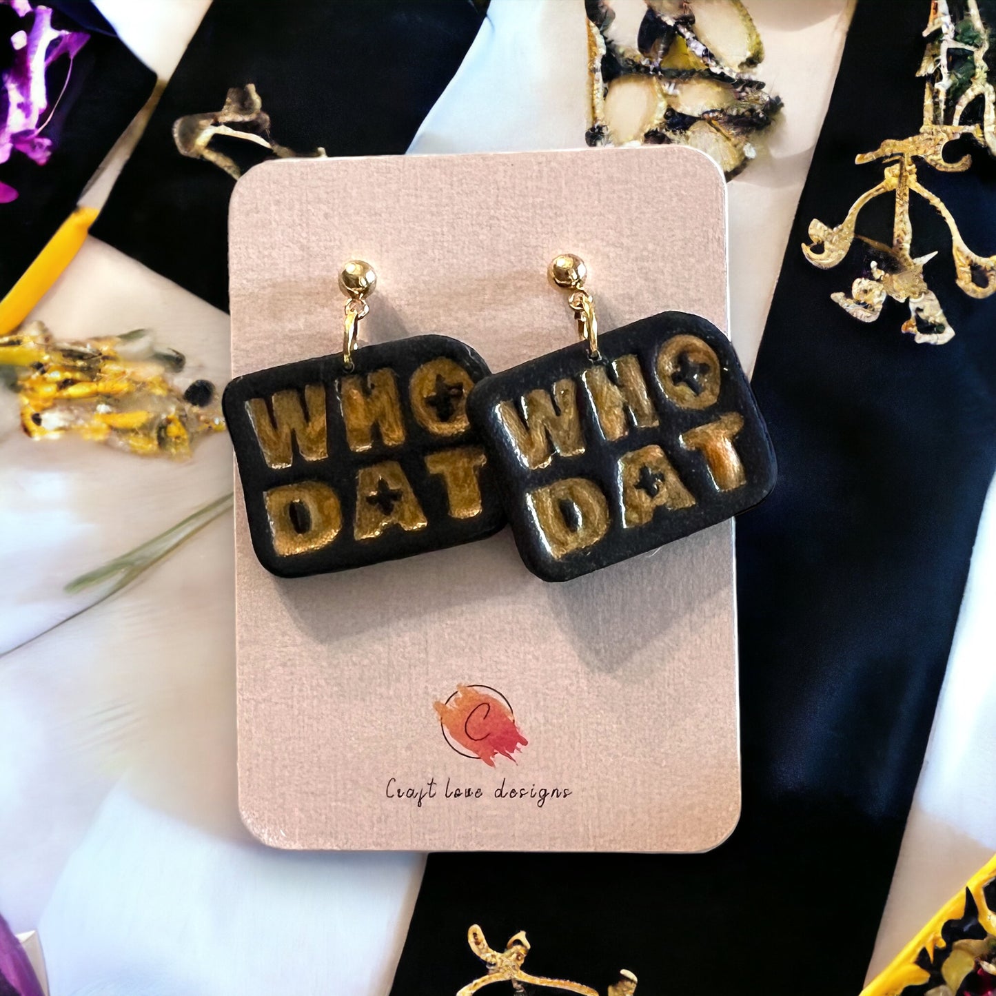 Black polymer clay earrings featuring bold golden WHO DAT text, inspired by sports team spirit. Fun and festive accessory.