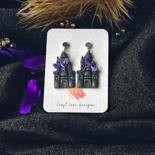 Gothic castle-themed earrings with purple bat accents displayed on a Craft Love Designs card, set against a dark, sparkly background.
