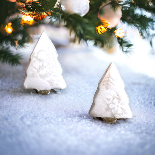 estive white Christmas tree stud earrings displayed on snowy ground under a decorated Christmas tree.