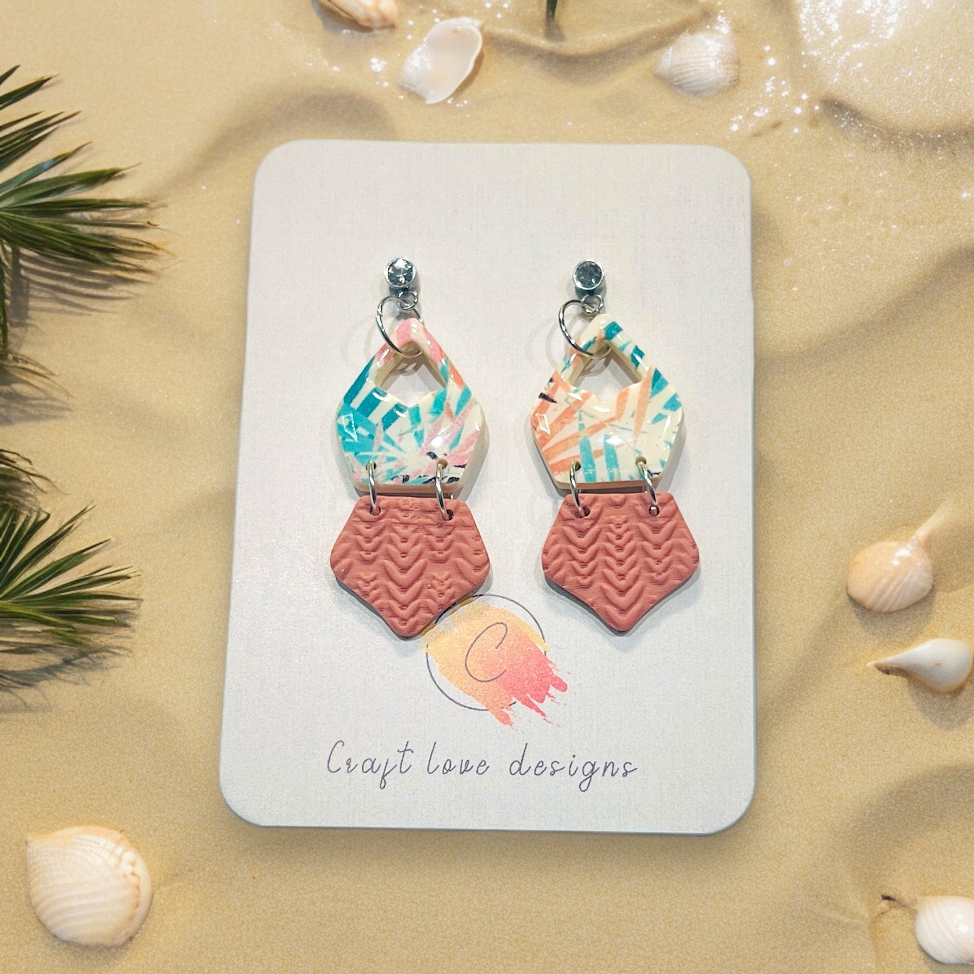 Handmade multicolor polymer clay earrings, elegantly mounted on Craft Love Designs' branded card with beach-themed details.
