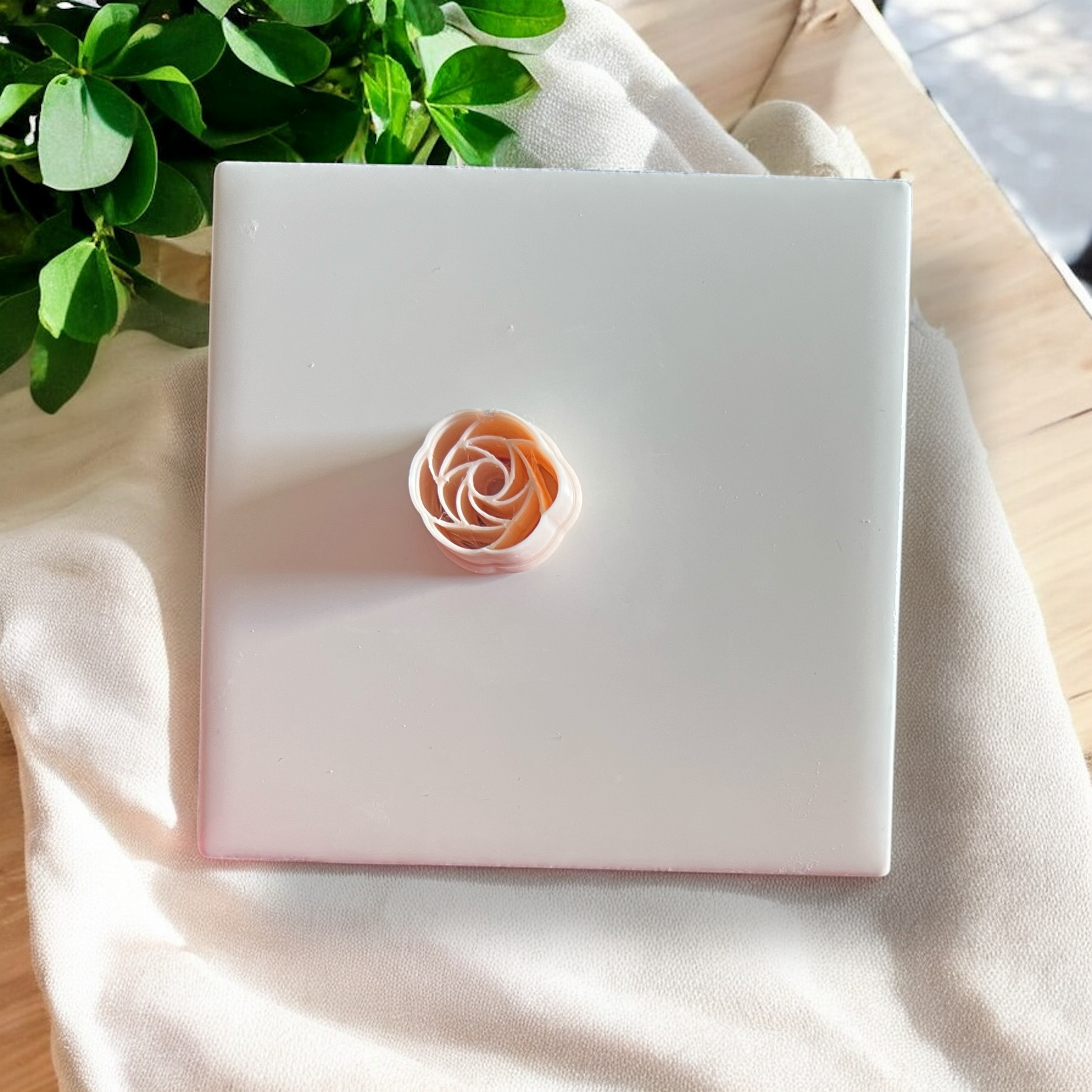 peach-toned polymer clay rose topper with soft shadows and greenery

