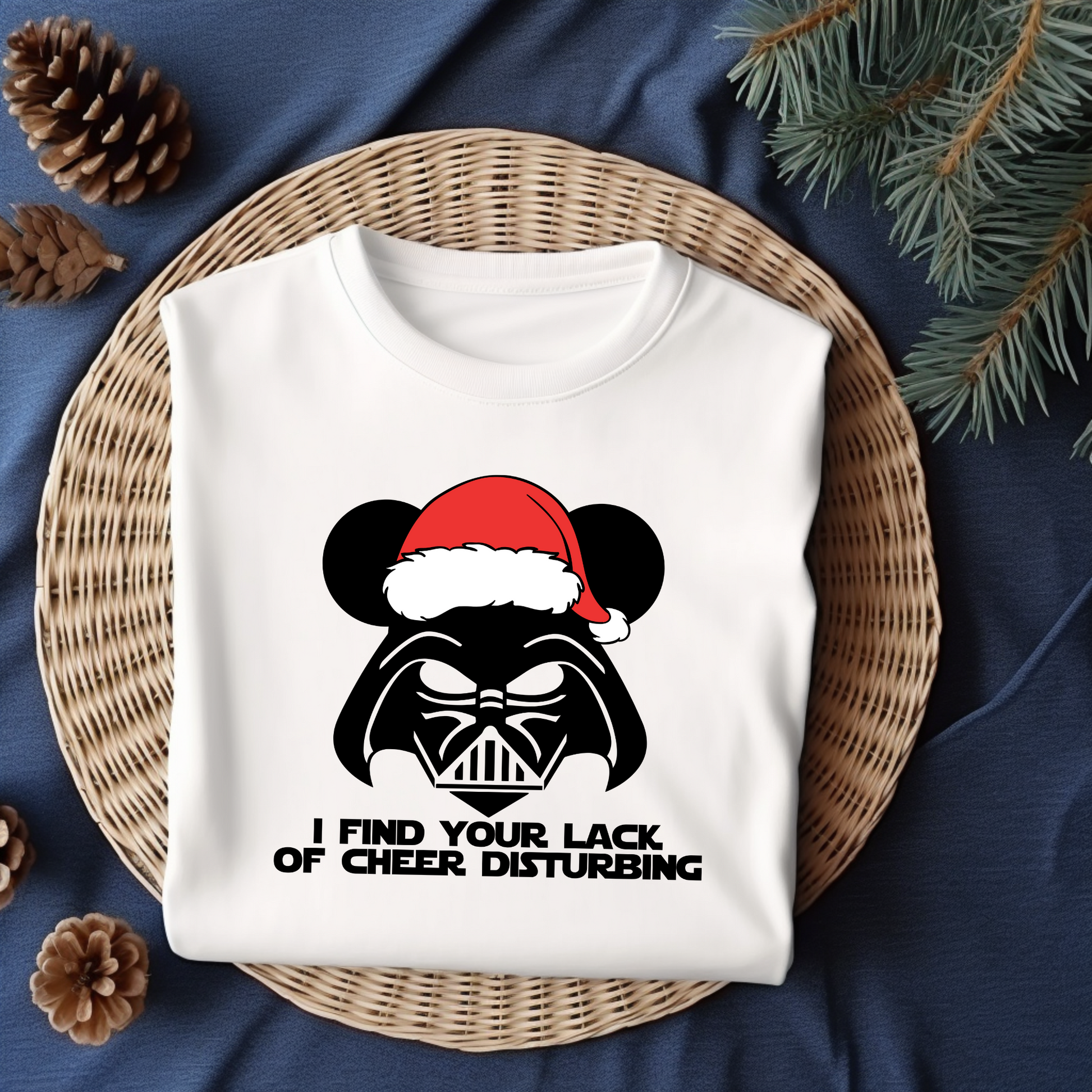 Flat lay of a white t-shirt featuring a Darth Vader-inspired design with mouse ears and a Santa hat, paired with the phrase "I Find Your Lack of Cheer Disturbing."