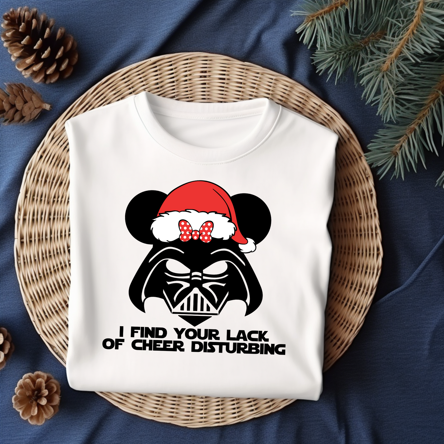 Flat lay of a white t-shirt featuring a Darth Vader-inspired design with mouse ears and a Santa hat, paired with the phrase "I Find Your Lack of Cheer Disturbing."