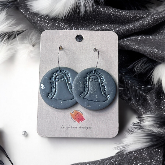 Circular earrings with ghost imprint displayed on a Craft Love Designs card, set against black and white feathers with glitter details.