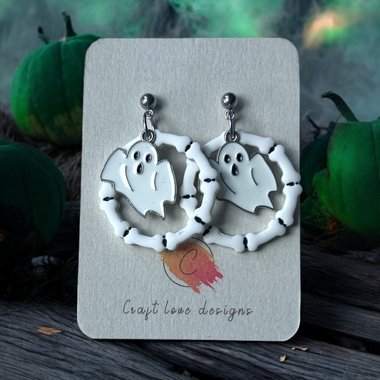 Polymer clay ghost earrings framed by bone hoops, displayed on Craft Love Designs card with a spooky green and pumpkin background.