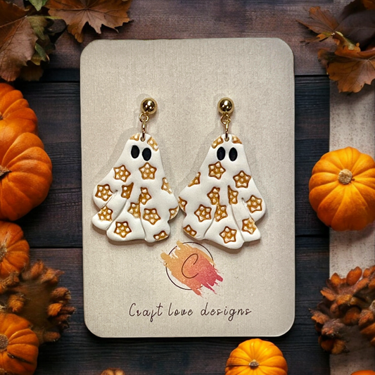 Polymer clay ghost earrings featuring gold flower patterns, mounted on a Craft Love Designs card with festive pumpkin decor in the background. 