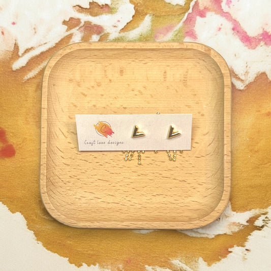 Gold V tassel earrings displayed on a wooden tray, highlighting sleek design with dangling gold beads for an elegant look.
