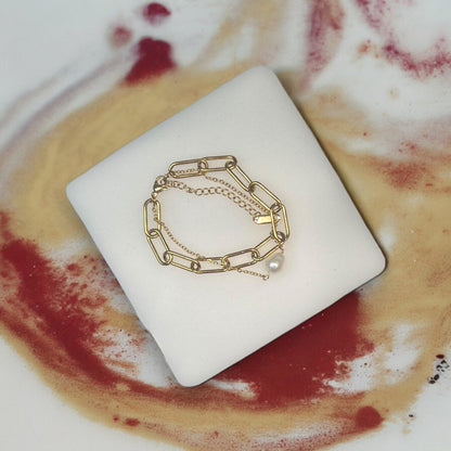 Sophisticated gold chain bracelet with pearl accent, stacked for a layered look. Ideal for adding a touch of elegance to any outfit.