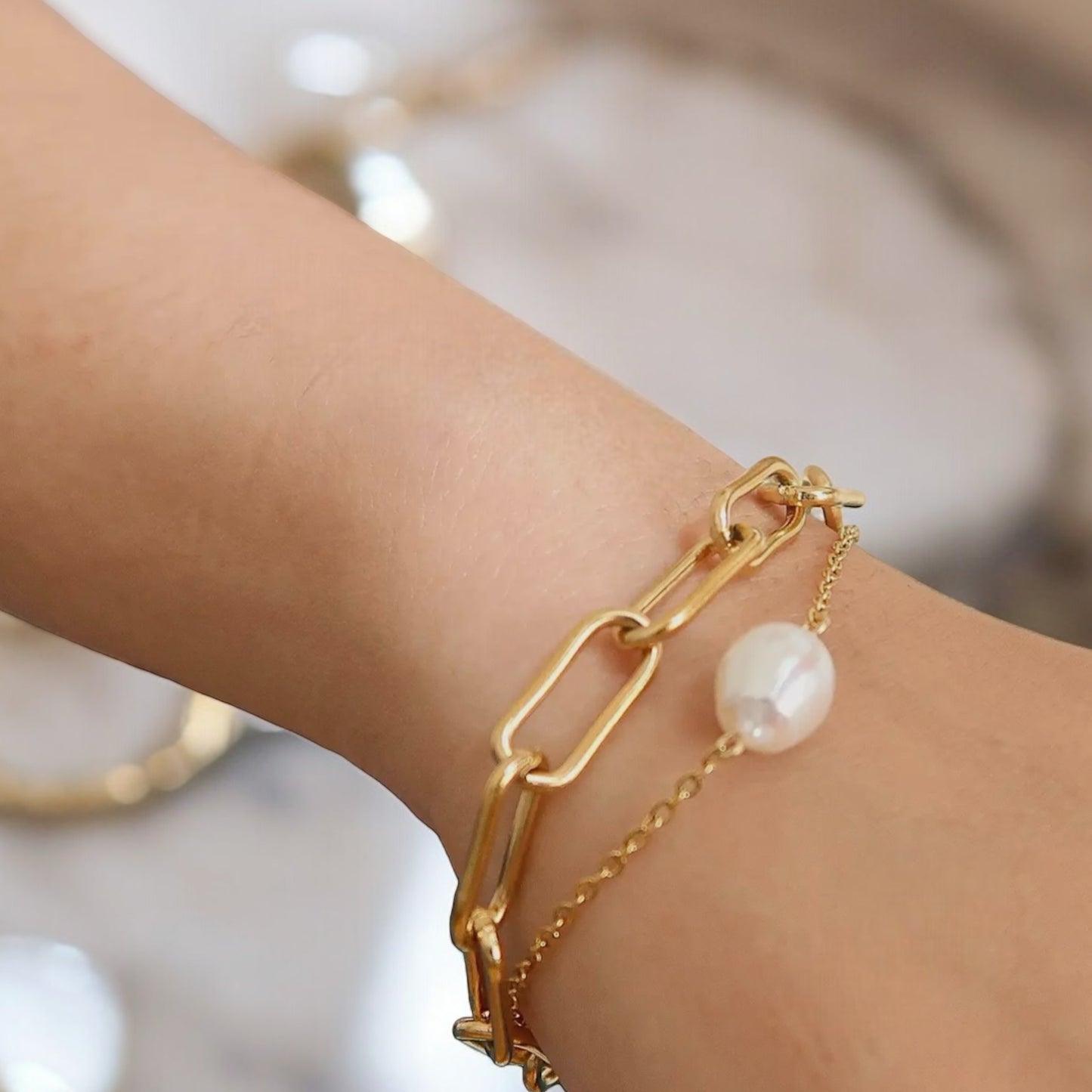 Elegant gold-stacked chain bracelet featuring a delicate pearl accent. The perfect statement accessory for any stylish and modern outfit.