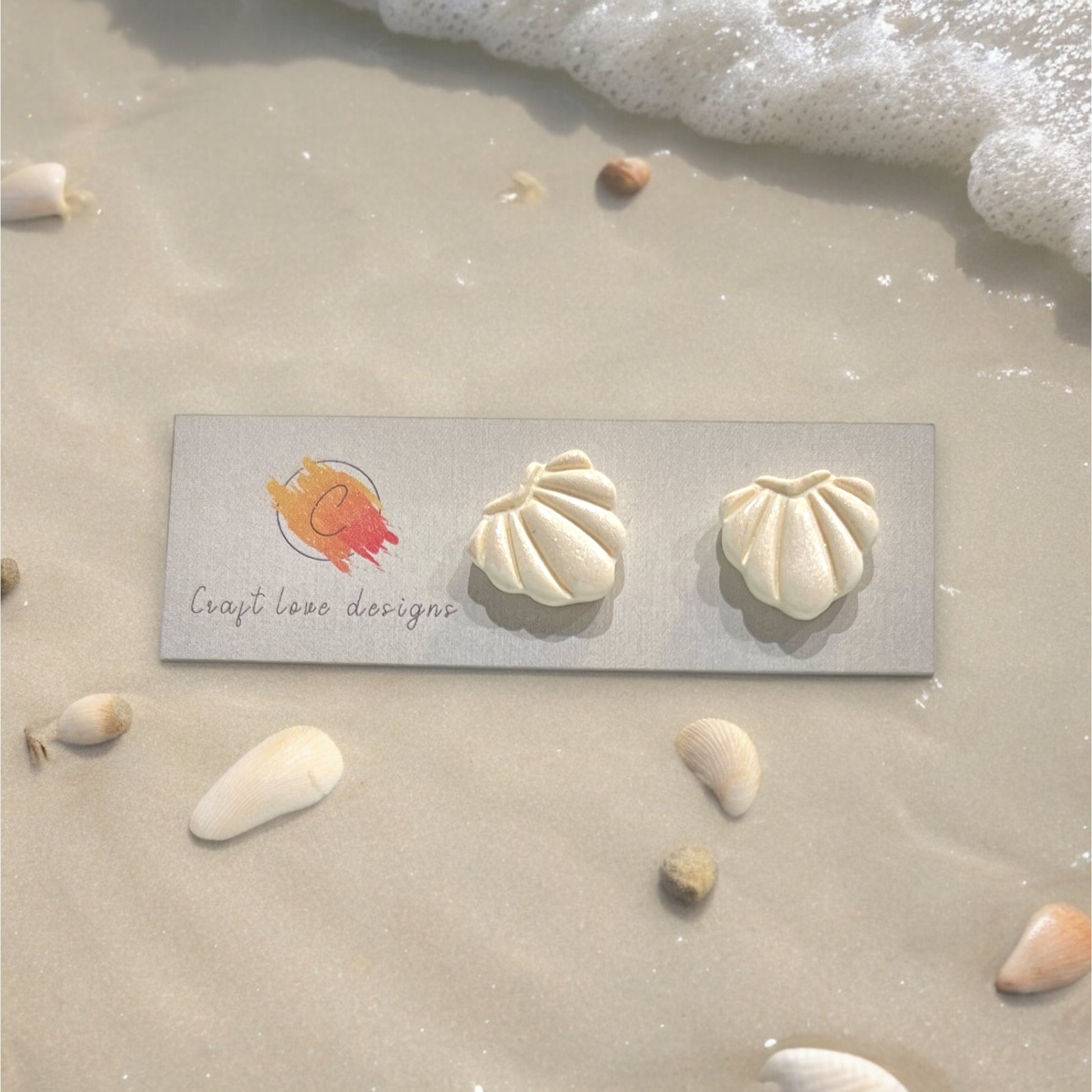 Elegant ivory seashell-shaped stud earrings on a textured coastal-themed backdrop. Perfect for summer beach vibes.