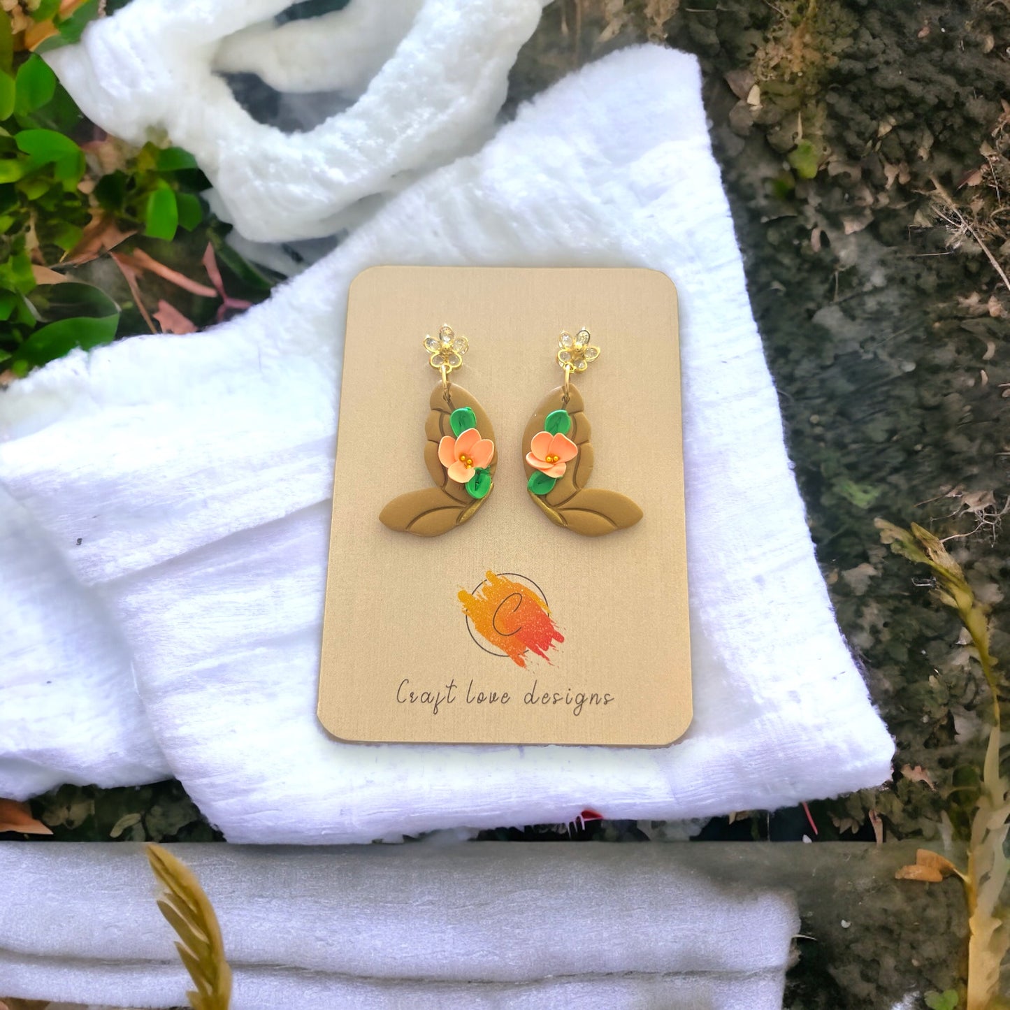 Latte and coral butterfly dangle earrings on a craft display, featuring soft floral accents and a nature-inspired design.