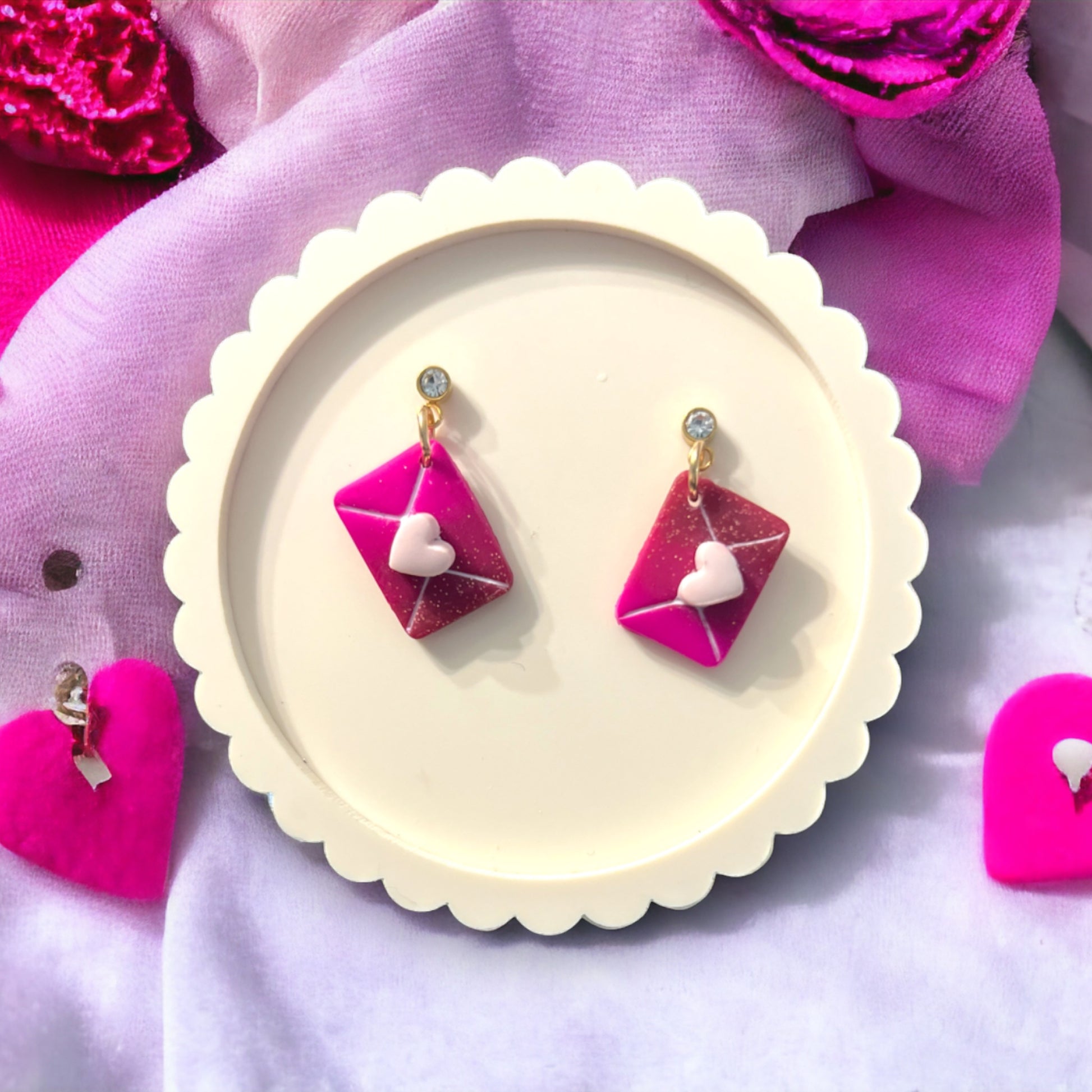 Hot pink letter-shaped earrings featuring a white heart on gold accents, perfect for adding charm to any outfit. 