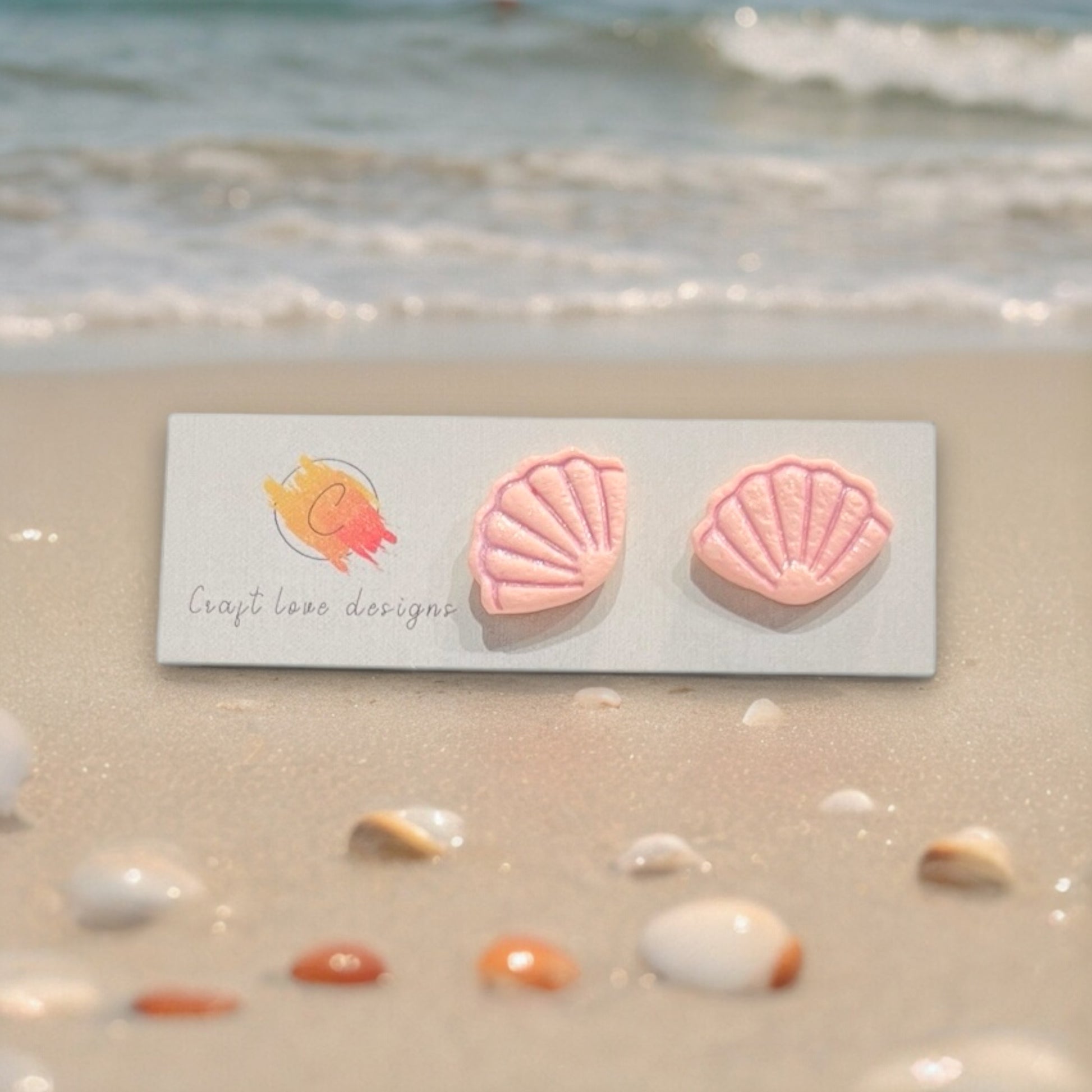Pink seashell earrings displayed on a decorative white round tray, creating a soft beach-inspired aesthetic.