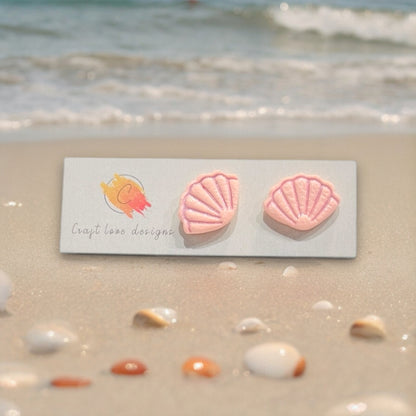 Pink seashell earrings displayed on a decorative white round tray, creating a soft beach-inspired aesthetic.