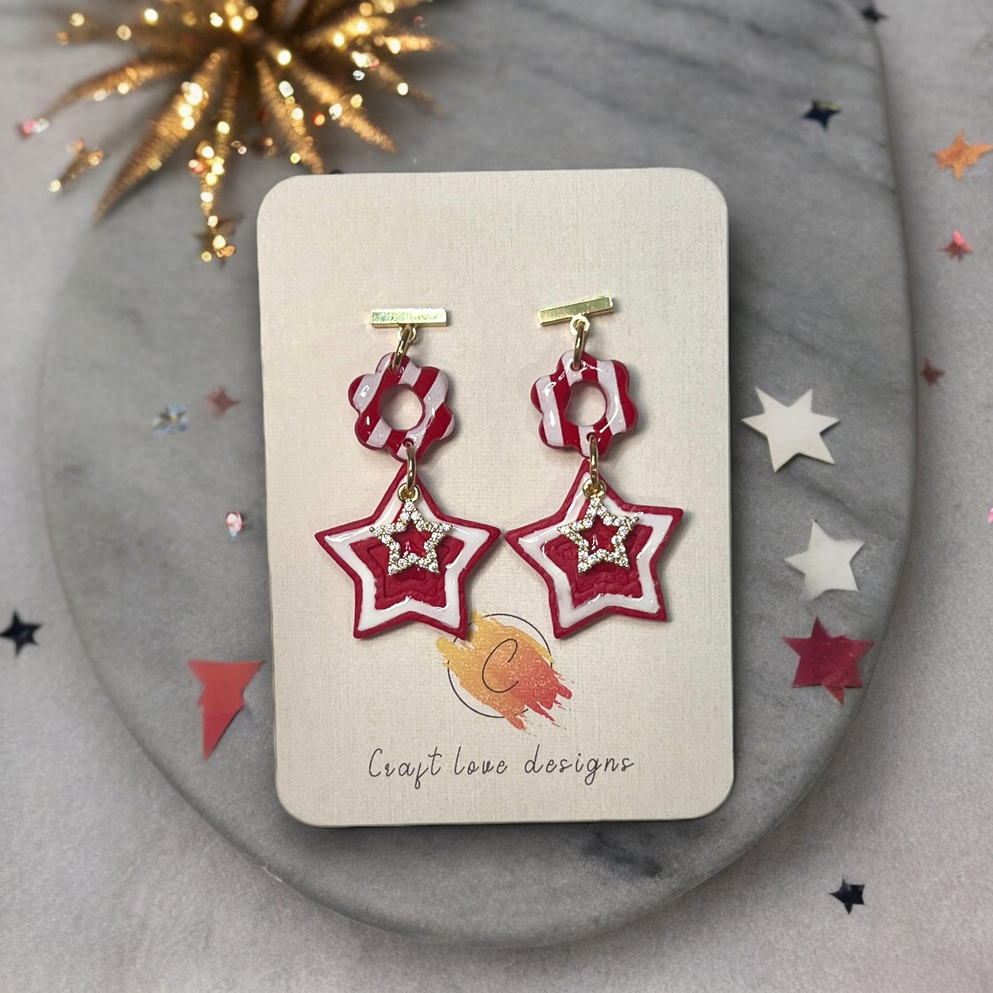 Red festive 4th of July polymer clay dangle earrings with bold, vibrant details, perfect for patriotic holiday celebrations on an earring card.