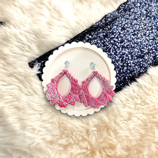 A pair of red and silver CZ dangle earrings with textured design placed on a decorative white round tray, perfect for adding a statement look.