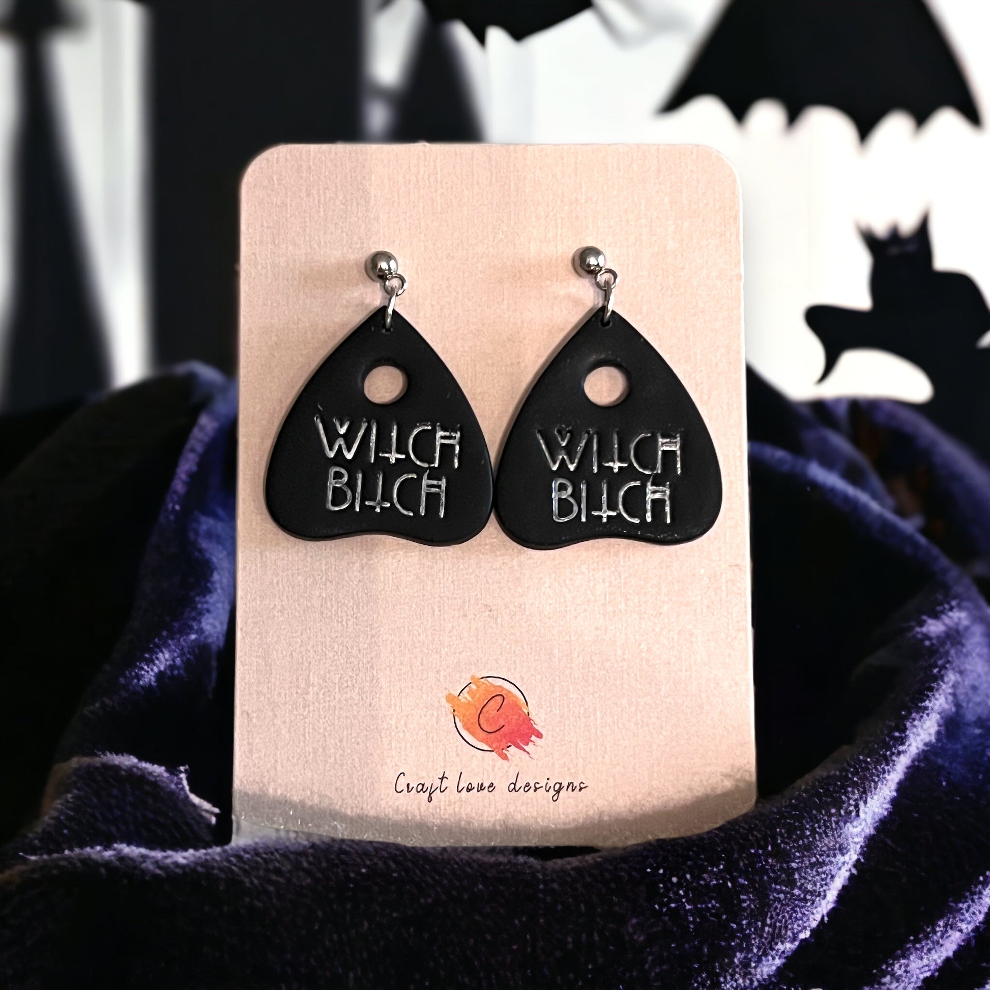 Black triangular dangle earrings featuring silver lettering, perfect for Halloween or spooky-themed outfits.