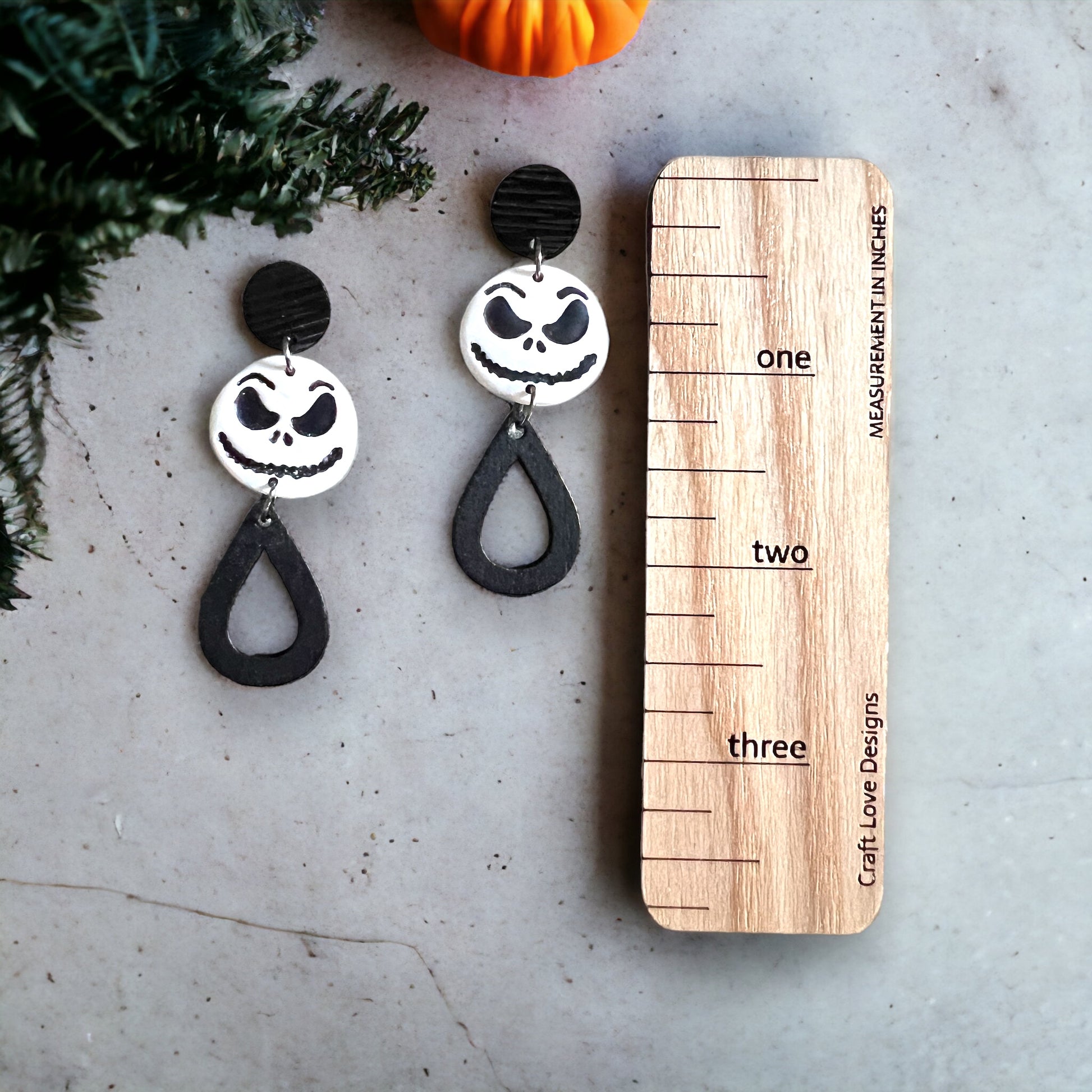  Black and White “Jack” dangle earrings shown with a measuring ruler, teardrop accents, and spooky charm perfect for festive looks.
