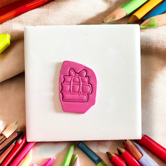 Pink shaped books on a white block with colorful pencils around