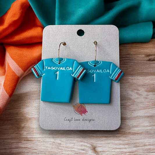 Front view of teal Tua Tagovailoa jersey-shaped polymer clay dangle earrings with customizable options, displayed on branded card.