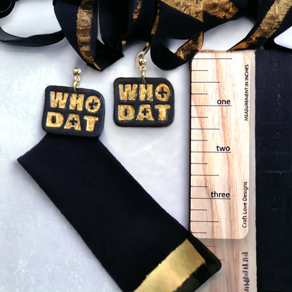 Rectangular black polymer clay earrings with WHO DAT embossed in gold. Eye-catching, bold, and playful for game day or everyday wear.