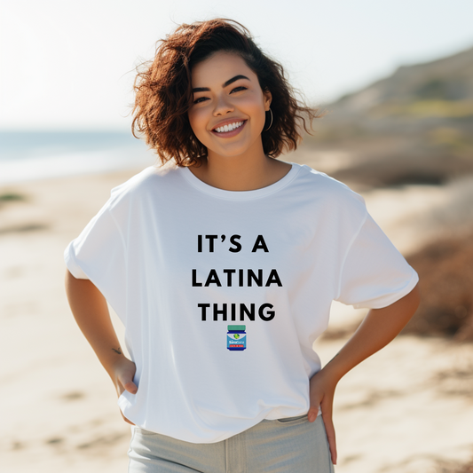 Woman wearing a white t-shirt featuring the phrase "It's a Latina Thing" in bold black letters with a small Vicks-themed icon, styled casually.