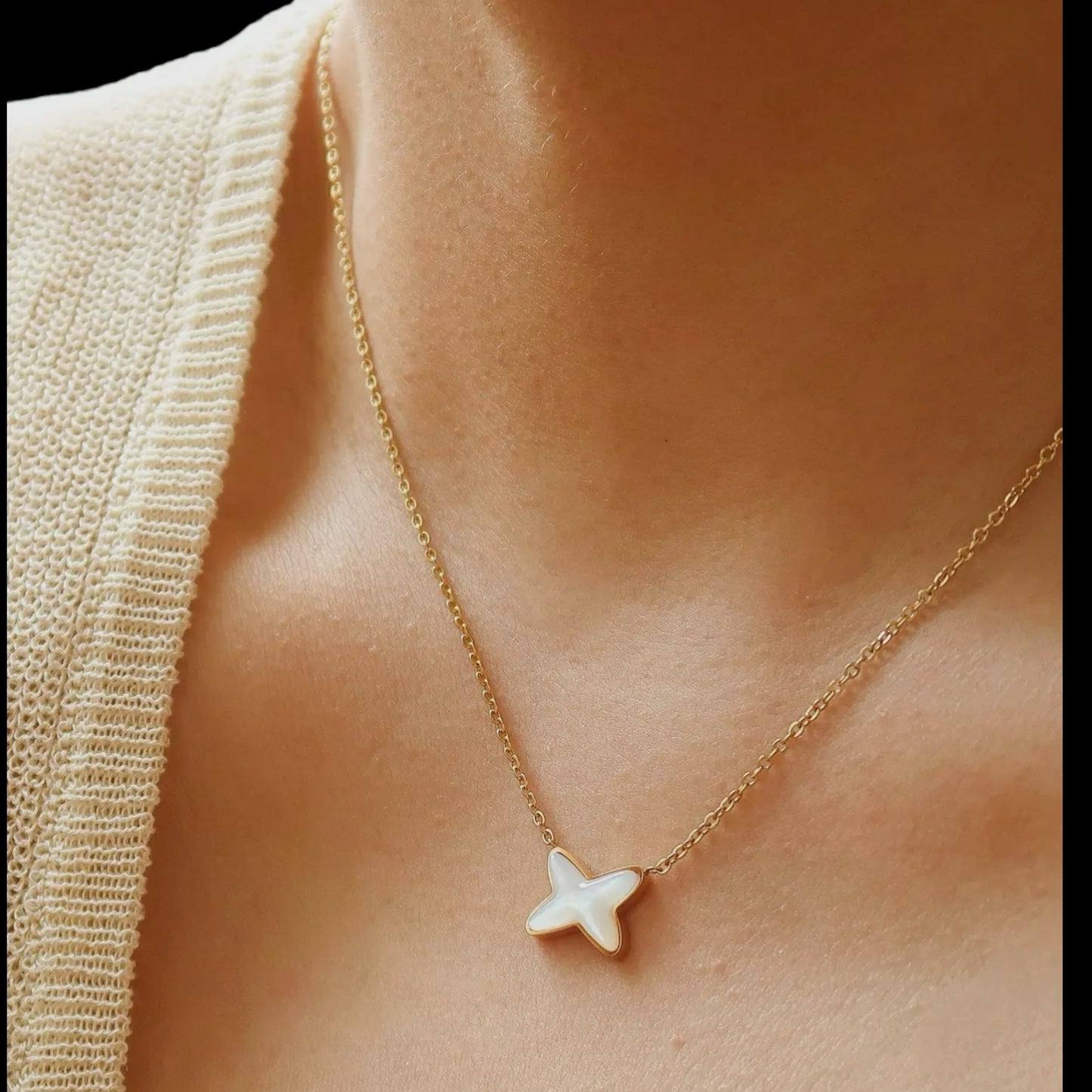 Petite gold necklace with an X shell pendant, worn by a model. The minimal design complements casual and formal styles with elegance.