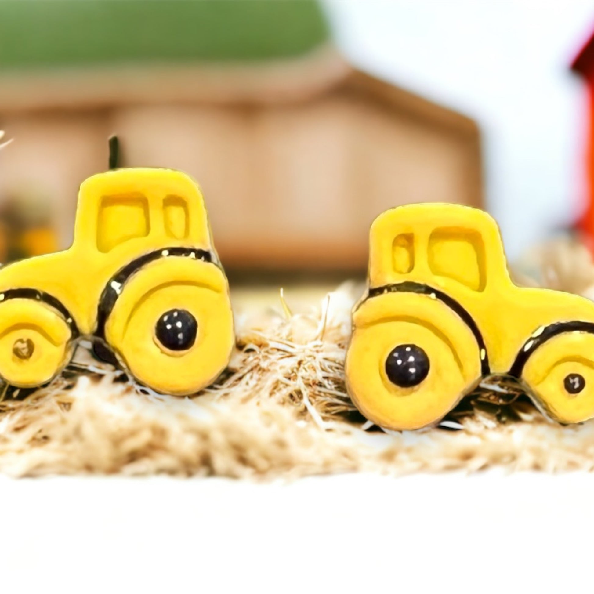 Bright yellow tractor-shaped stud earrings placed on a rustic background with a charming farm aesthetic. 