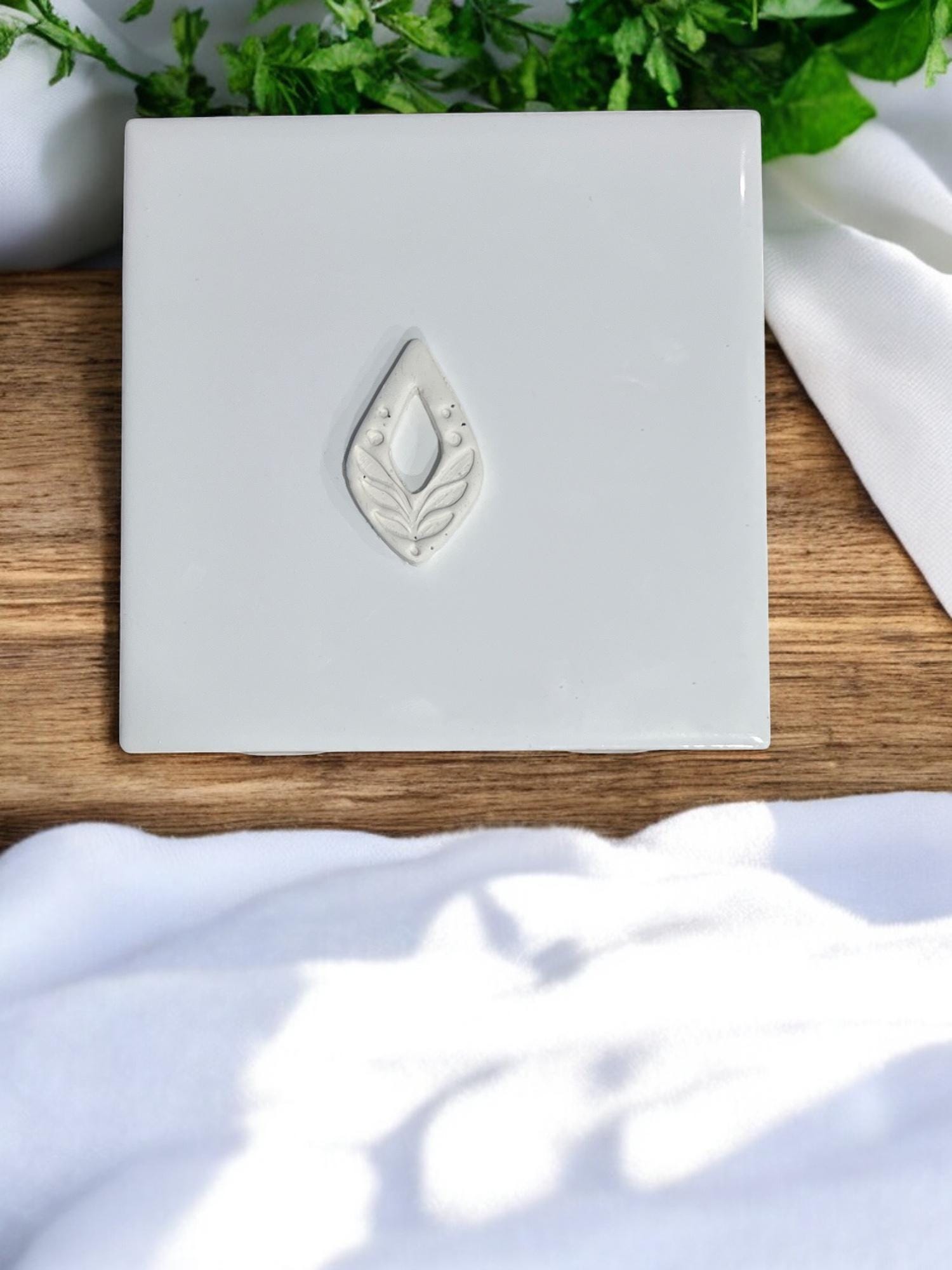 Close-up of single embossed clay piece featuring folk leaf pattern