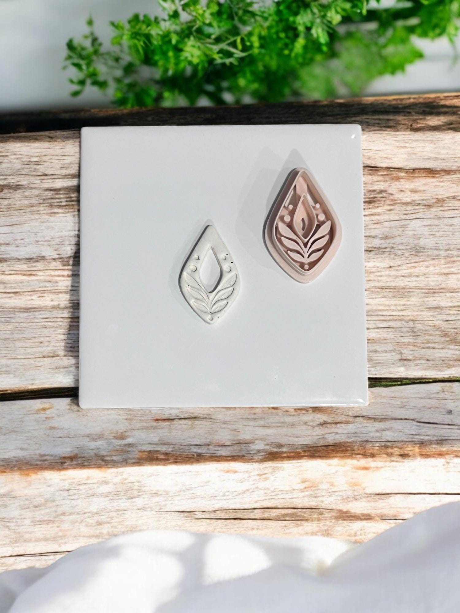 Embossed drop leaf clay design with matching cutter on white ceramic tile