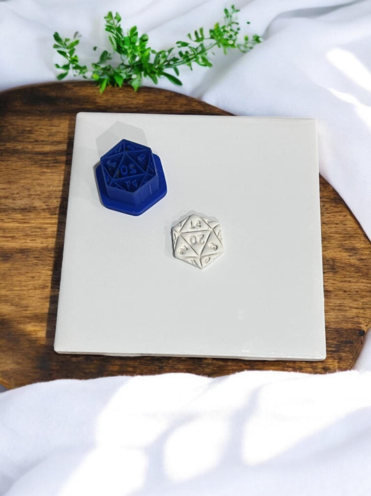 Navy blue D20 clay cutter next to matching clay result on tile