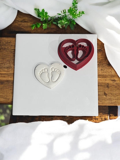 Red polymer clay cutter beside finished heart with feet imprint
