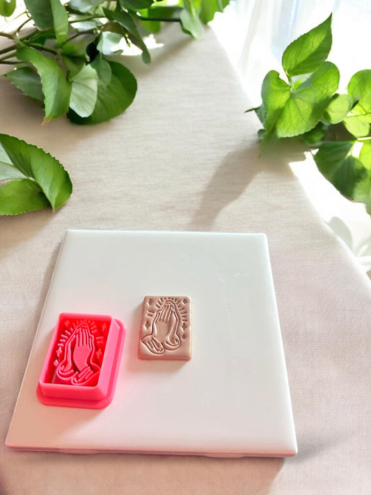 A side-by-side image of the praying hands cutter and the finished clay piece, showcasing the precision of the imprint