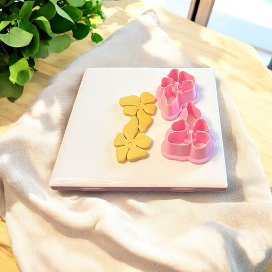 Clay earring shapes next to pink interlocking floral cutters, showing the complete dangle earring setup
