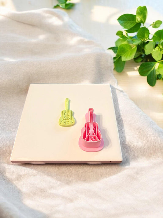Side-by-side of finished guitar clay piece and pink polymer clay cutter, showing star flag details in an island music style