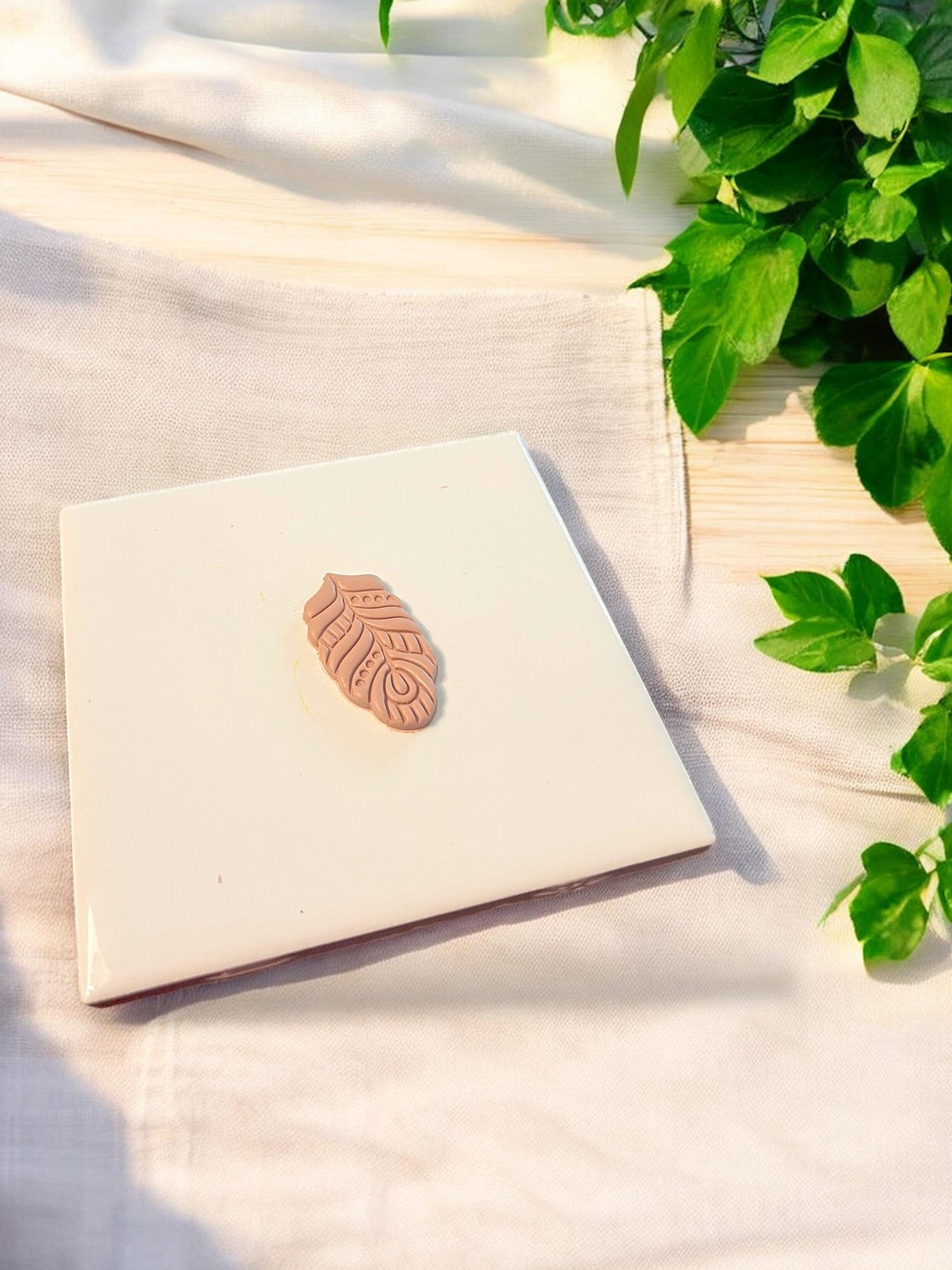 A close-up of a clay feather shape in warm tones, ideal for creating bold boho dangle earrings using polymer clay