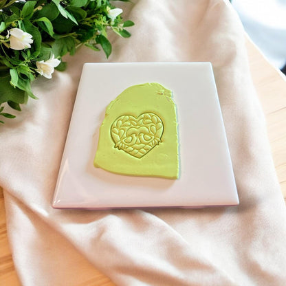 Lime green slab of polymer clay with detailed heart-shaped impression of love birds and florals.
