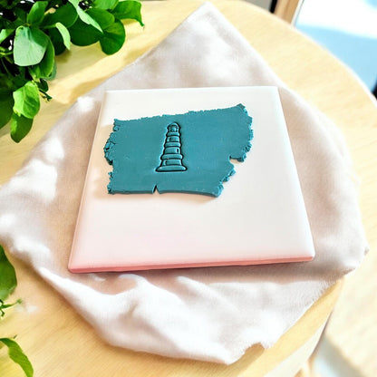 3D-printed lighthouse-shaped clay cutter placed on a slab of polymer clay, showcasing its design.