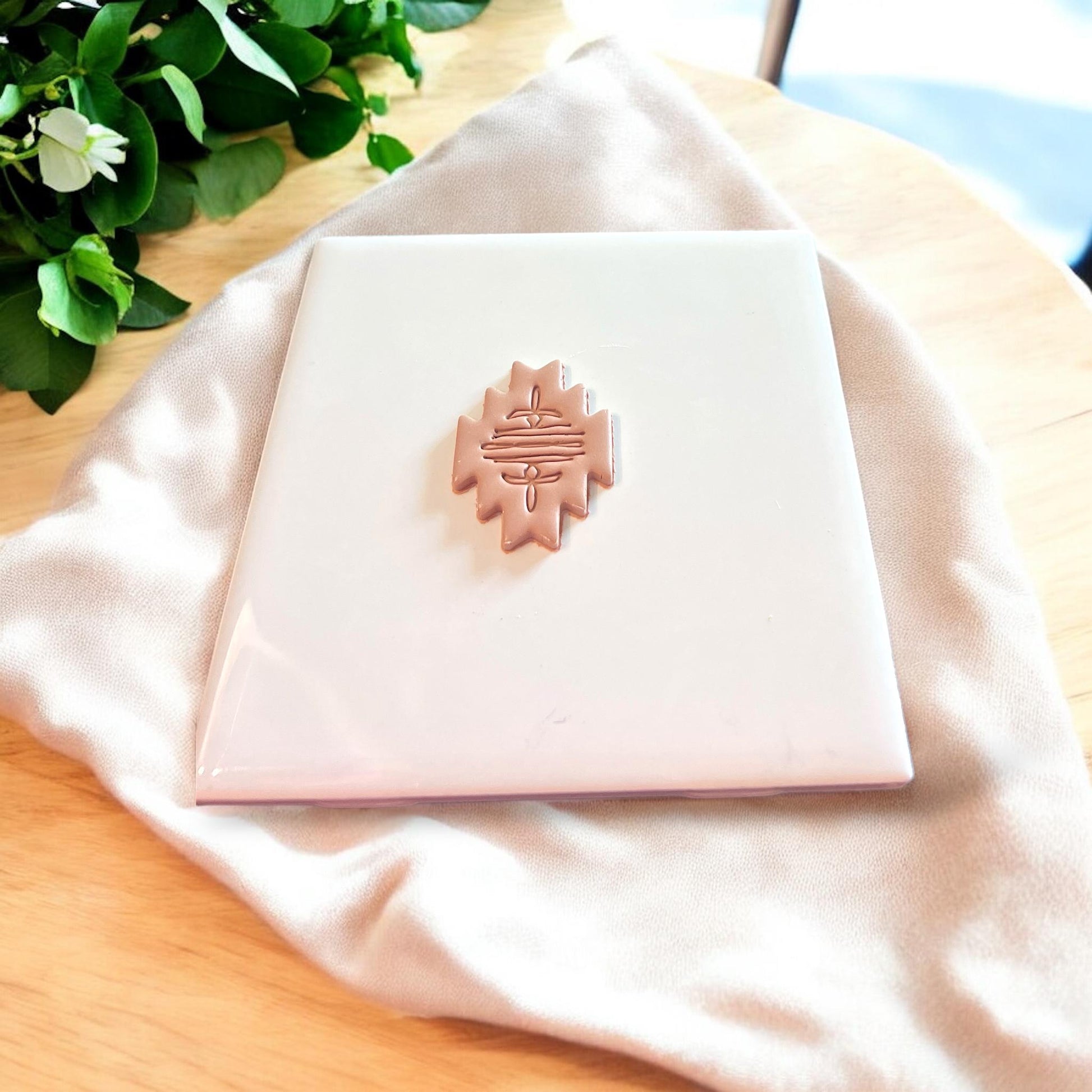 Finished boot stitch clay earring piece shown alone on ceramic tile for detail visibility