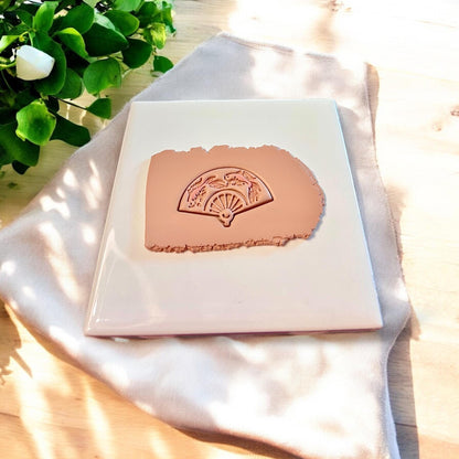 Clay slab stamped with detailed koi fan design from polymer clay cutter in soft tan clay