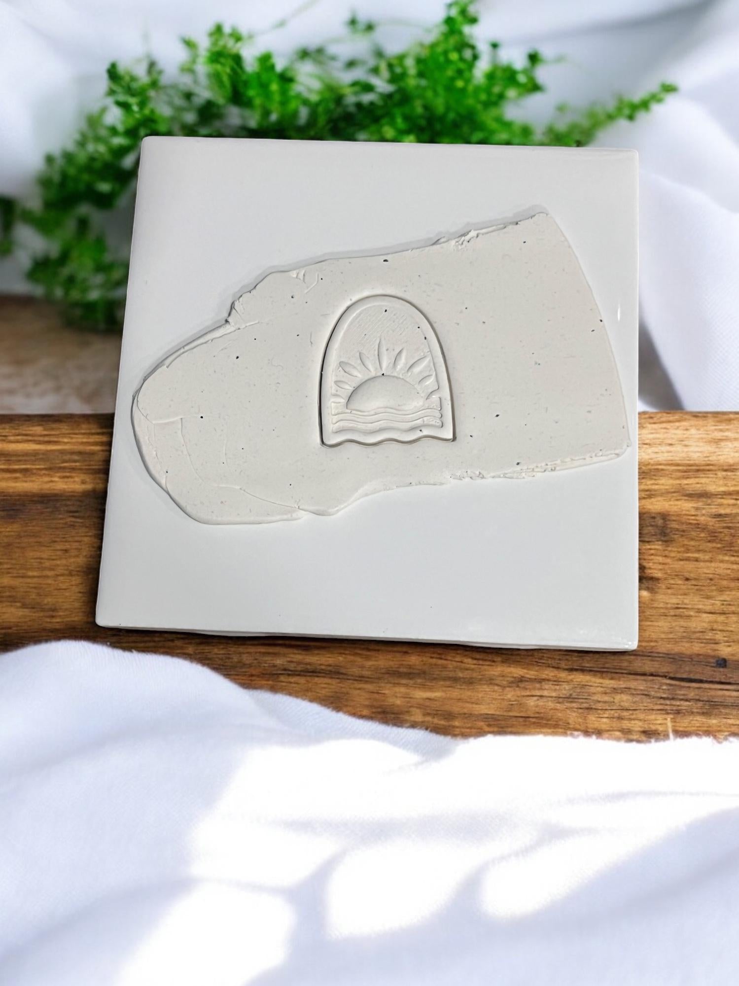 Embossed sunrise design pressed into clay slab on ceramic tile