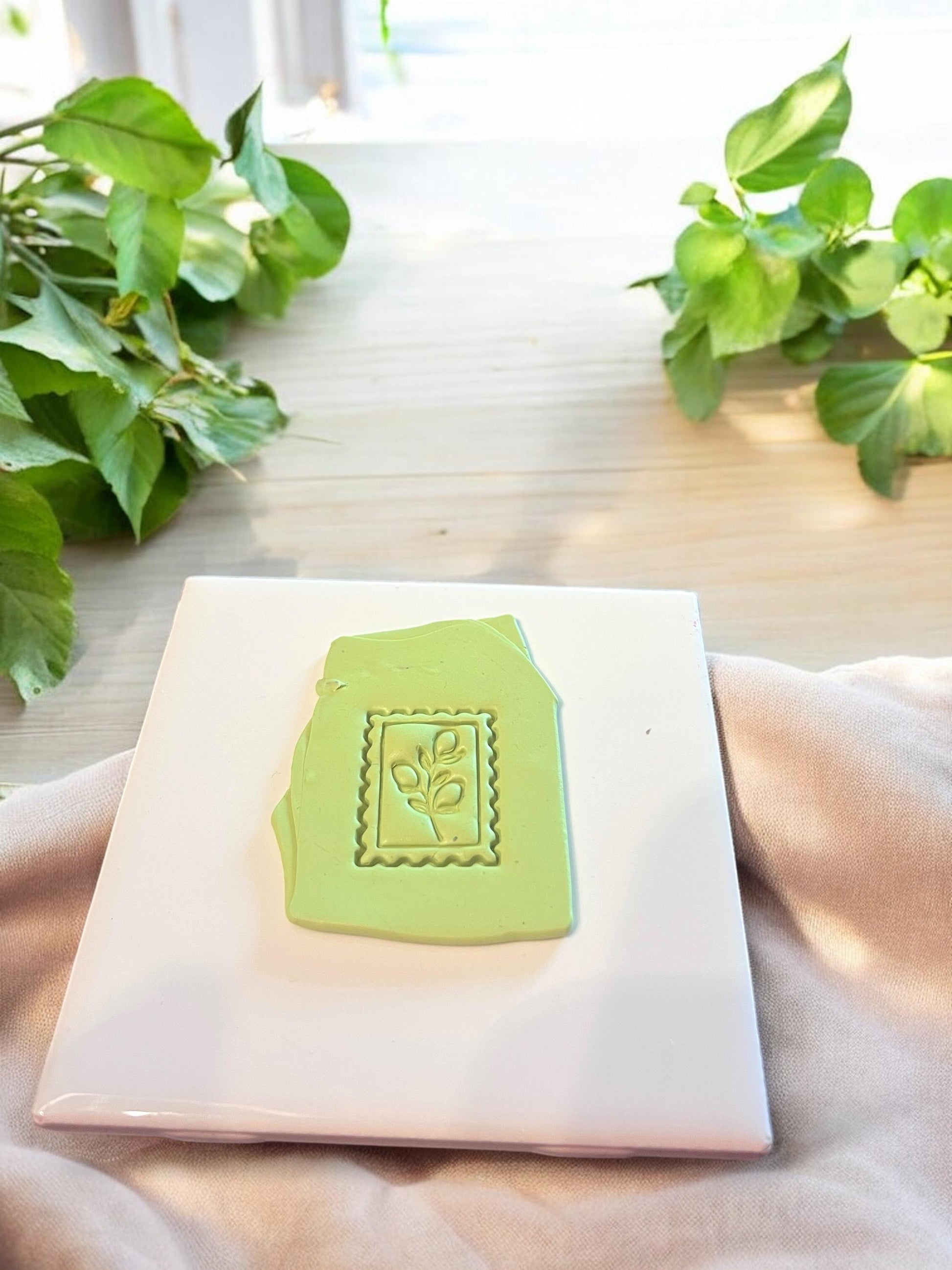 Green lemon stamp impression on clay slab, showcasing a playful citrus leaf design ideal for summer jewelry making.