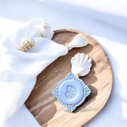 Finished polymer clay seashell piece on wood with seashell props, perfect for boho coastal earring inspiration